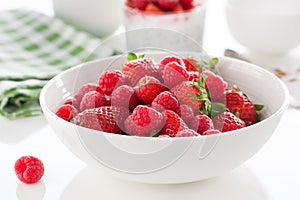 Summer fresh red juicy fruits Ã¢â¬â raspberries and strawberries in a white bowl on a table for breakfast or lunch